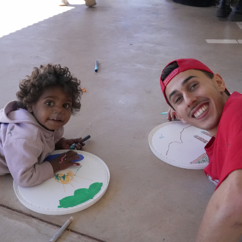 Red Dust volunteer Louie with young person painting