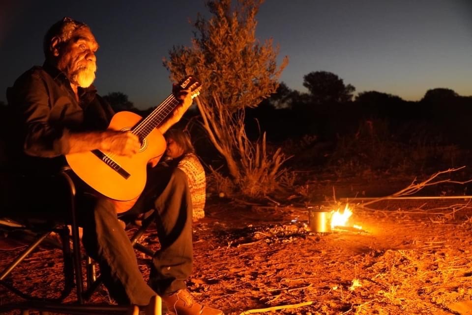 Ned Hargraves with guitar by the fire
